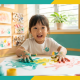 Young child painting joyfully in a modern Singapore preschool, surrounded by vibrant artwork.